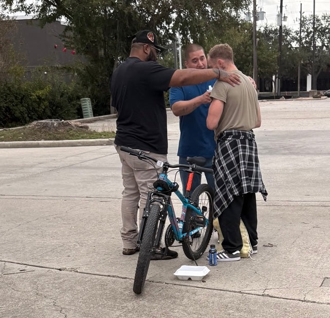 Outreach team praying with a person beside a bicycle